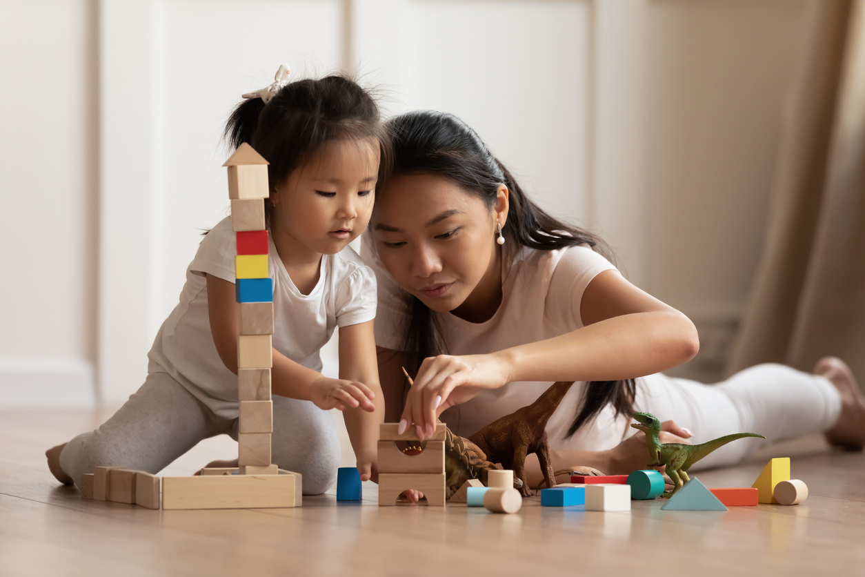 Daughter her mother play with blocks on the floor